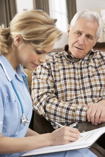 Senior man praten met gezondheid bezoeker thuis — Stockfoto