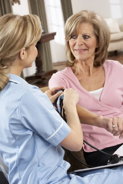 Visitante de salud tomando la presión arterial de la mujer mayor — Foto de Stock