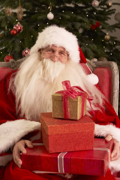 Papá Noel sentado en sillón delante del árbol de Navidad —  Fotos de Stock