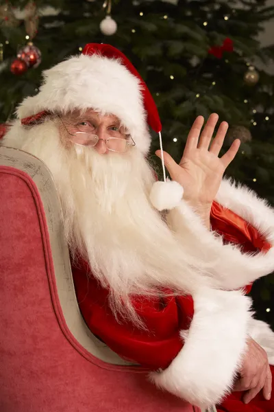 圣诞老人坐在扶手椅上前的圣诞树 — 图库照片