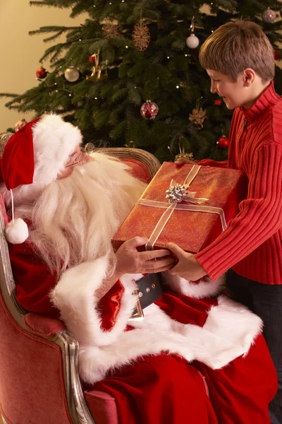 Santa claus geschenk geven jongen voorkant kerstboom — Stockfoto