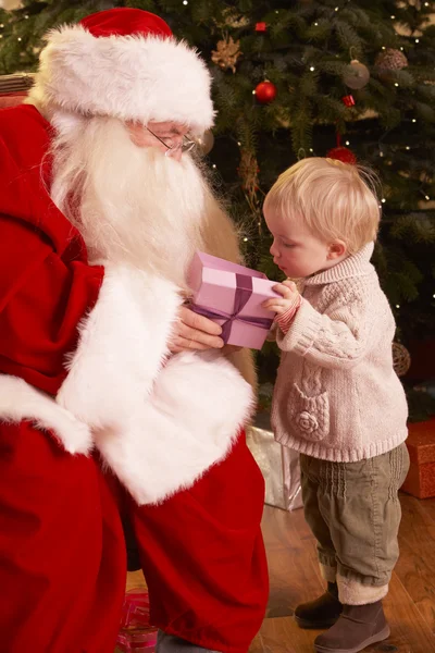 Weihnachtsmann beschenkt Jungen vor dem Weihnachtsbaum — Stockfoto