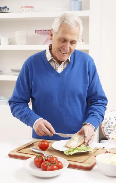 Uomo anziano che fa sandwich in cucina — Foto Stock