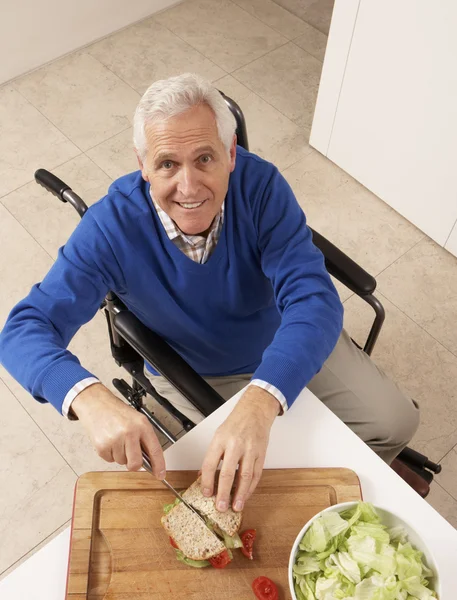 Старший инвалид делает сэндвич на кухне — стоковое фото
