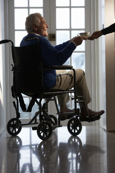 Homme âgé handicapé assis dans un fauteuil roulant étant remis tasse — Photo