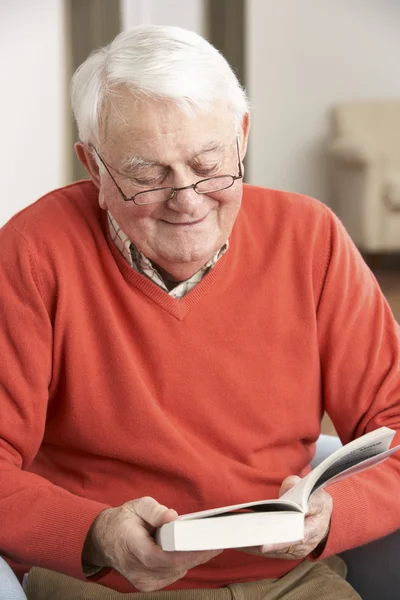 Starszy człowiek, relaks w fotelu w domu czytanie książki — Zdjęcie stockowe