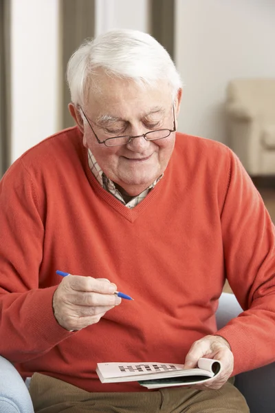 Relaxační křesla doma starší muž vyplnění křížovky — Stock fotografie