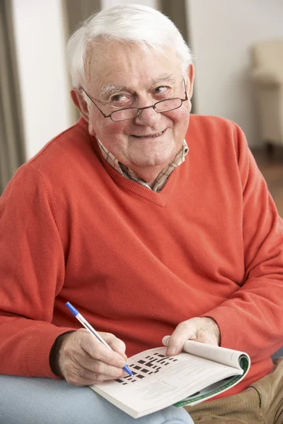 Senior Man Relaxing In Chair At Home Completing Crossword — Stock Photo, Image