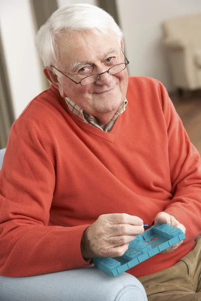 Senior man sorteren medicatie organisator thuis gebruiken — Stockfoto