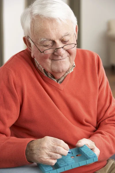 Starszy mężczyzna sortowania leków za pomocą organizatora w domu — Zdjęcie stockowe