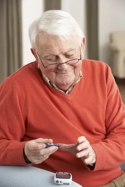 Senior kontrolliert Blutzuckerspiegel zu Hause — Stockfoto
