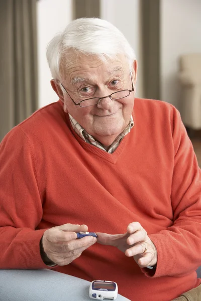 Oudere man die thuis bloedsuikerspiegel controleert — Stockfoto