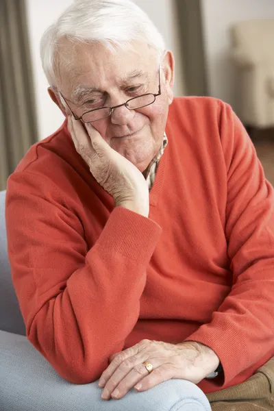 Homme âgé regardant triste dans la chaise à la maison — Photo