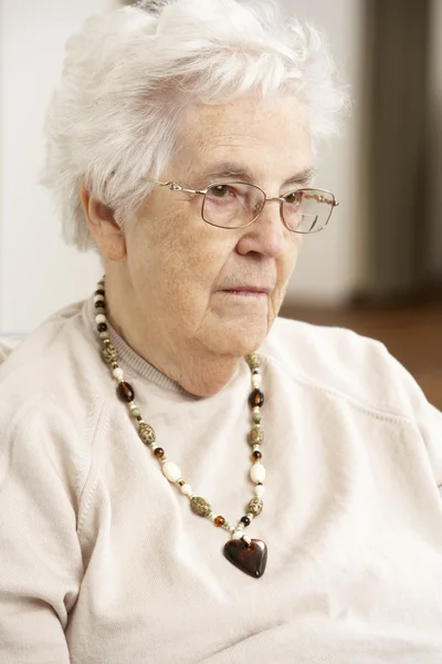 Anziana donna guardando triste in sedia a casa — Foto Stock