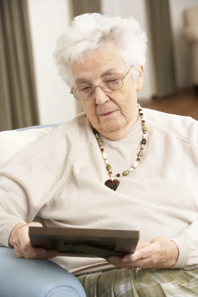 Donna anziana guardando la fotografia in cornice — Foto Stock