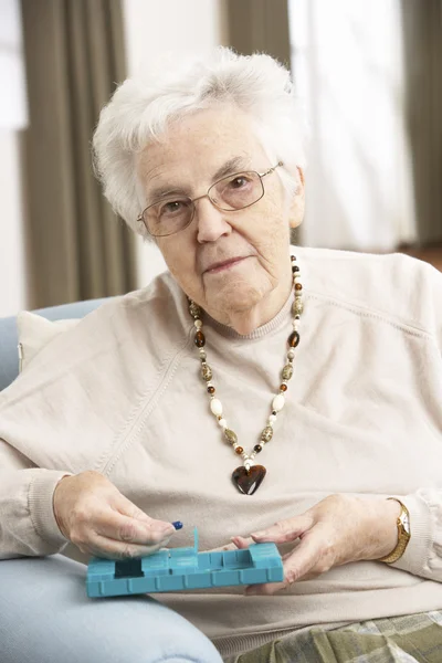 Senior vrouw sorteren medicatie organisator thuis gebruiken — Stockfoto