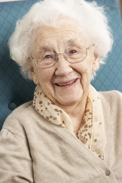 Starsza kobieta relaks w fotelu w domu — Zdjęcie stockowe