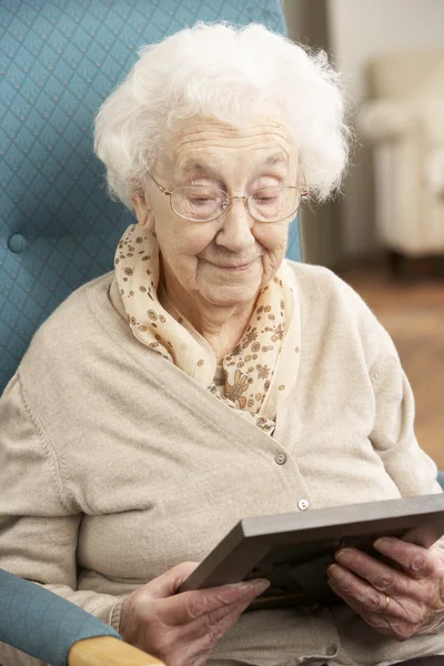 Ledsen äldre kvinna som tittar på fotografiet i ram — Stockfoto