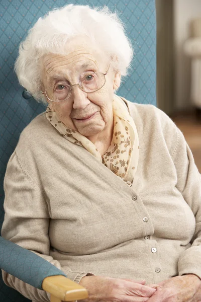 Femme âgée regardant triste dans la chaise à la maison — Photo
