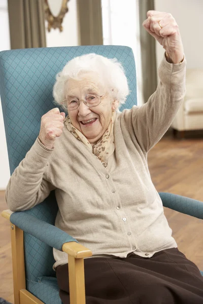 Mujer mayor celebrando en silla en casa — Foto de Stock