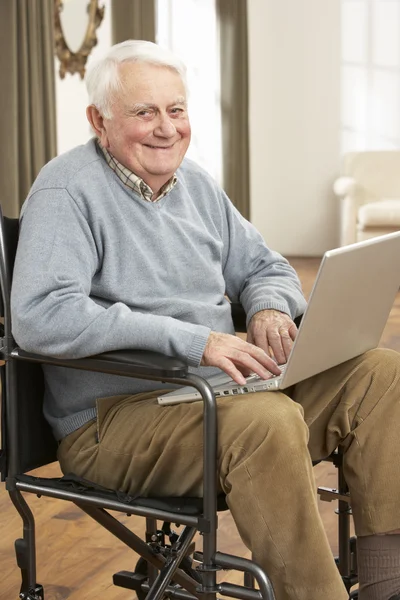 残疾的老人坐在轮椅上使用的便携式计算机 — 图库照片