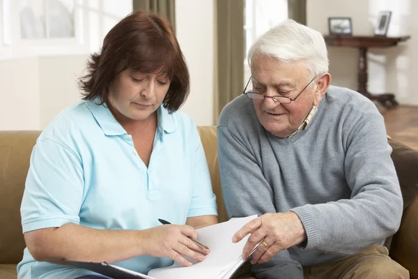 Äldre man i diskussion med hälsa besökare hemma — Stockfoto