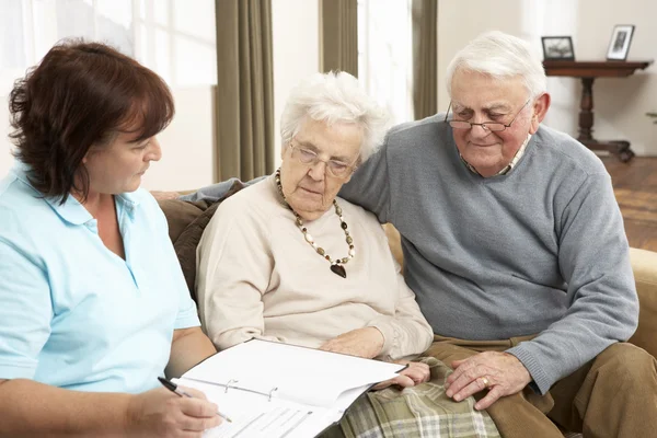 Äldre par i diskussion med hälsa besökare hemma — Stockfoto