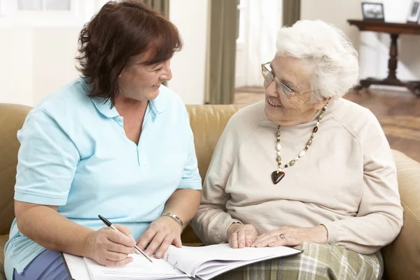 Femme âgée en discussion avec un visiteur de la santé à la maison — Photo
