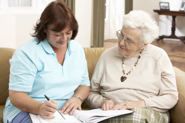 Donna anziana in discussione con la salute Visitatore a casa — Foto Stock