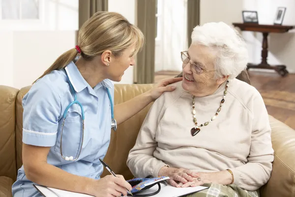 Femme âgée en discussion avec un visiteur de la santé à la maison — Photo