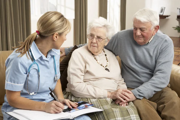 Couple âgé en discussion avec un visiteur de la santé à la maison — Photo