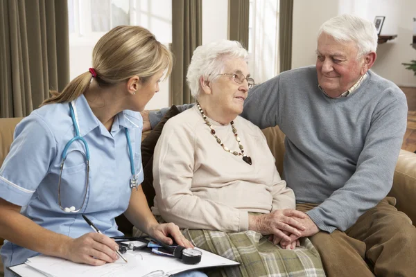 Старшая пара в обсуждении с посетителем здравоохранения на дому — стоковое фото