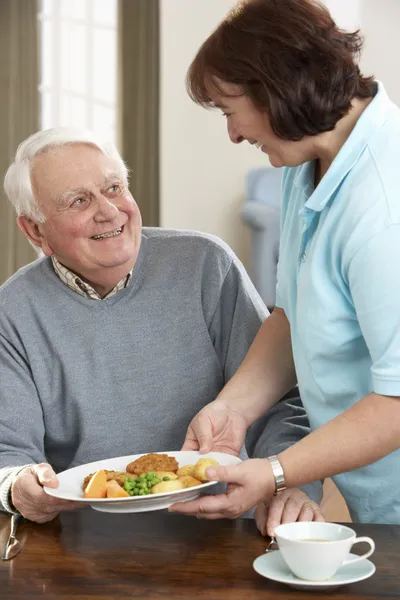 Hombre mayor siendo servido comida por cuidador — Foto de Stock