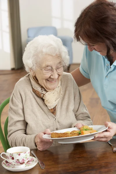 Senior mujer siendo servido comida por cuidador — Foto de Stock