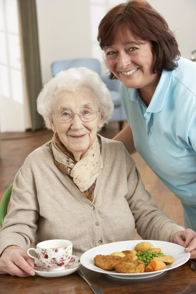 Senior vrouw maaltijd wordt geserveerd door verzorger — Stockfoto