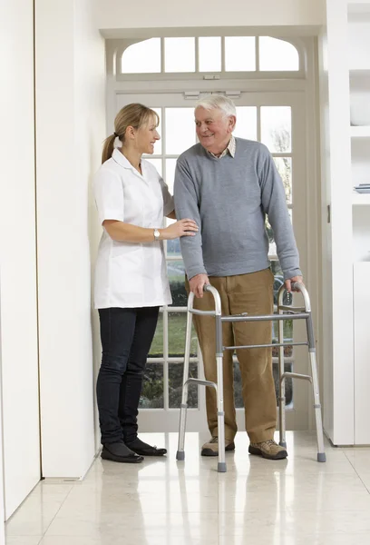 Cuidador que ayuda al anciano mayor a usar el marco para caminar — Foto de Stock