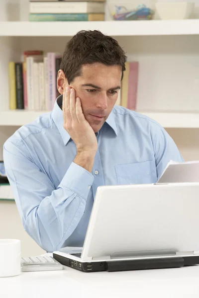Bezorgd uitziende man die werken vanuit huis met behulp van laptop — Stockfoto