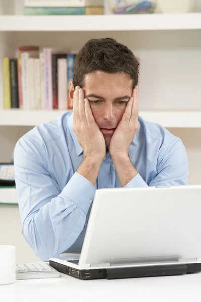Homem olhando preocupado que trabalha de casa usando laptop — Fotografia de Stock