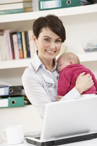 Žena s novorozeně pracující z domova pomocí přenosného počítače — Stock fotografie