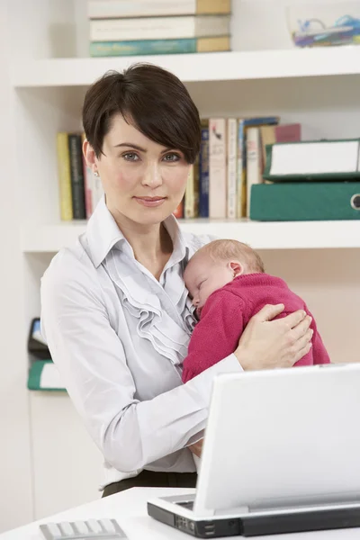 Žena s novorozeně pracující z domova pomocí přenosného počítače — Stock fotografie