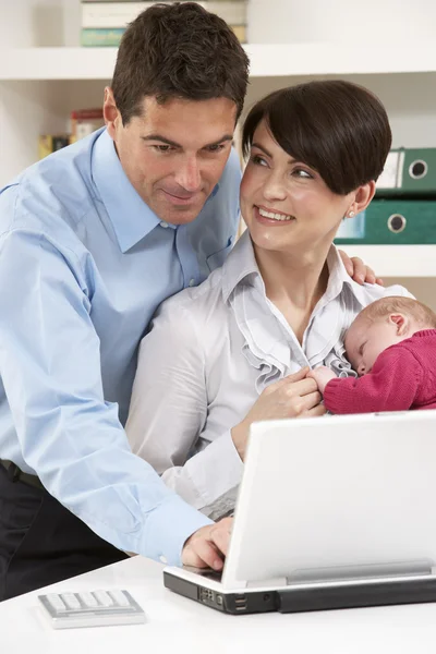 Родители с новорожденным ребенком работают из дома с помощью ноутбука — стоковое фото