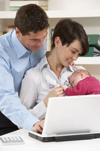 Pais com bebê recém-nascido trabalhando em casa usando laptop — Fotografia de Stock