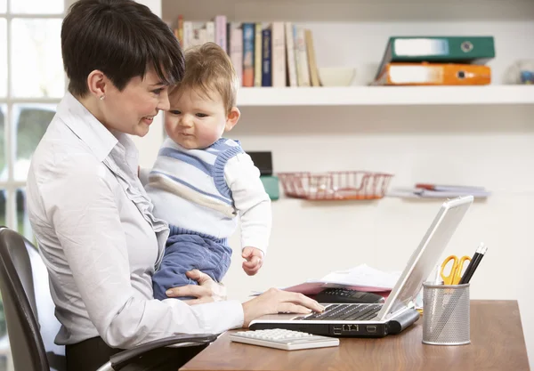 Женщина с ребенком работает из дома с помощью ноутбука — стоковое фото