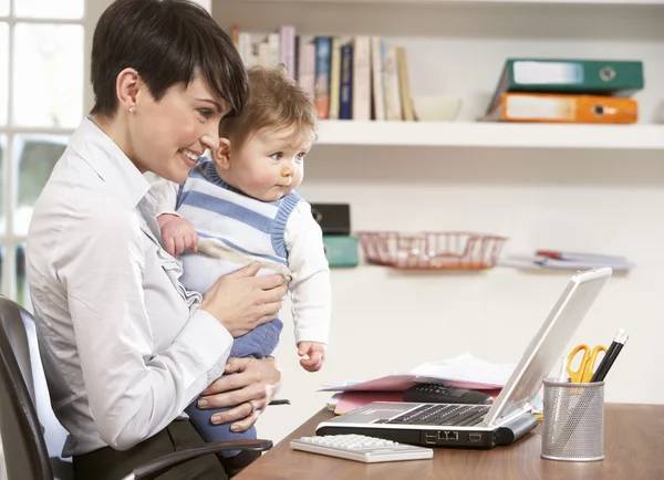 Vrouw met baby werken vanuit huis met behulp van laptop — Stockfoto