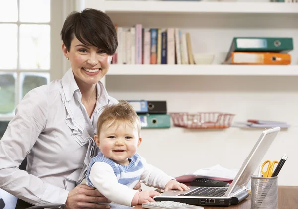 Mujer con bebé trabajando desde el hogar usando el ordenador portátil —  Fotos de Stock
