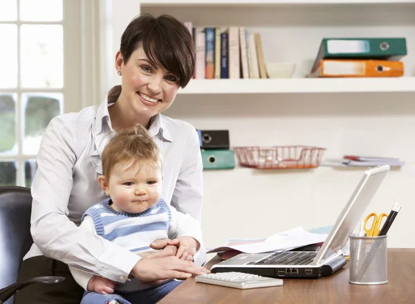 Женщина с ребенком работает из дома с помощью ноутбука — стоковое фото