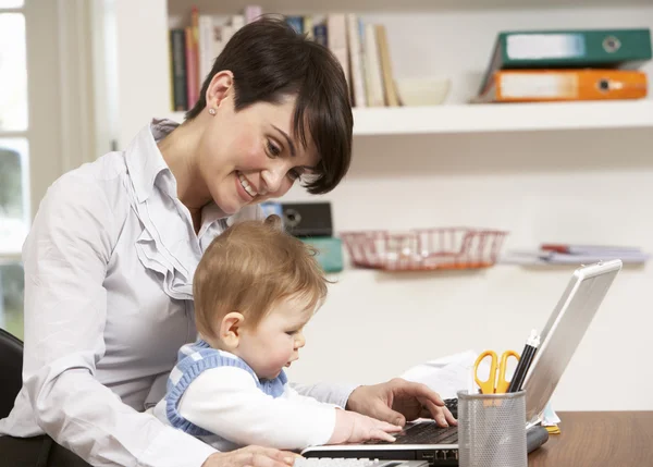 Mujer con bebé trabajando desde el hogar usando el ordenador portátil — Foto de Stock