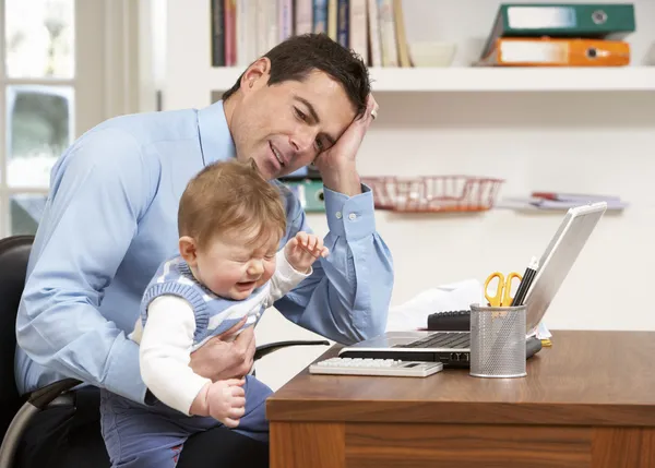 Benadrukt man met baby werken vanuit huis met behulp van laptop — Stockfoto