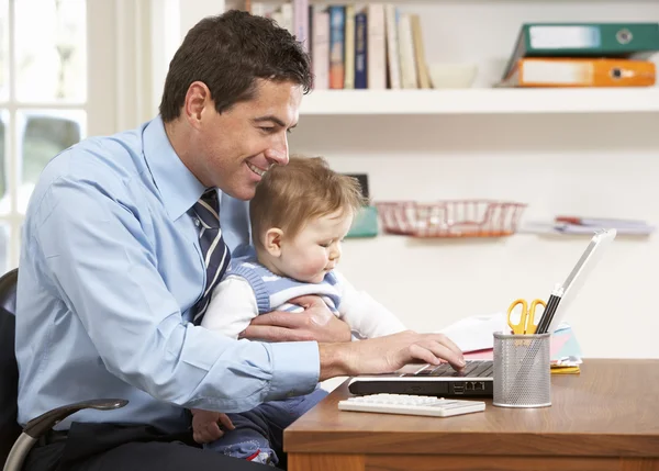 Man met baby werken vanuit huis met behulp van laptop — Stockfoto