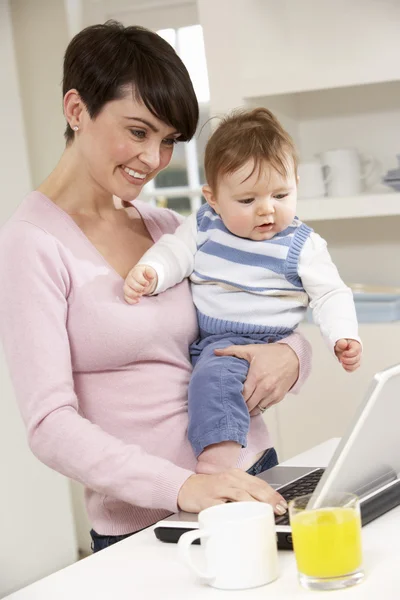 Evde dizüstü bilgisayar kullanan bebekli kadın. — Stok fotoğraf